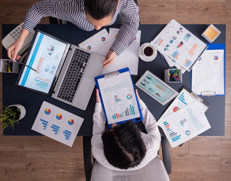 top-viewtop-view-manager-employee-doing-teamwork-business-office-looking-charts-laptop-display_482257-2443